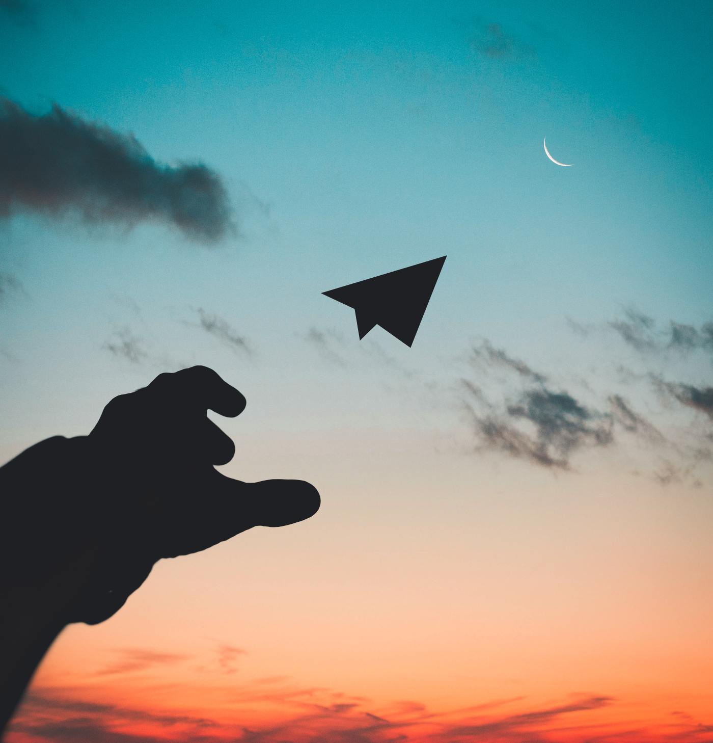 hand throwing a paper airplane into the sky with a sunset background