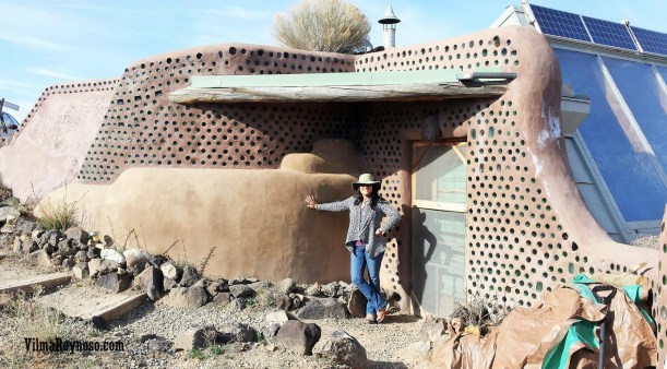 Vilma Reynoso standing in front of an earthship in New Mexico