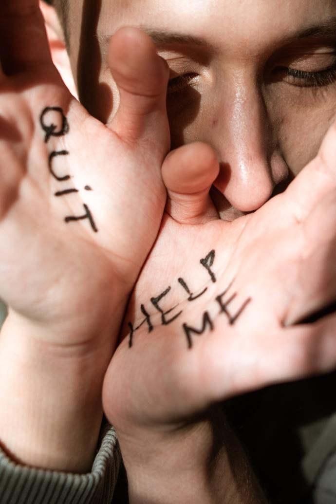 woman's hands in front of her face. On one hand is written Quit and on the other is written Help Me. Me too.