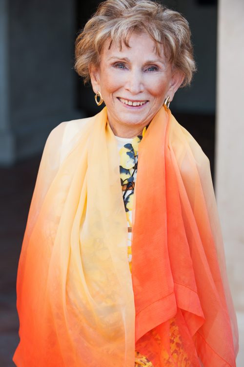 Eva Eger in orange dress, author of The Choice: Embrace the Possible, Book Review 