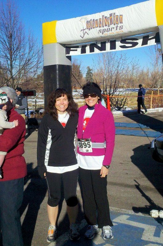 two women posing in front of a finish line sign after running a 5K