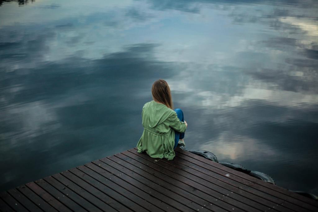 girl sitting on the edge of a roof with a troubled sky