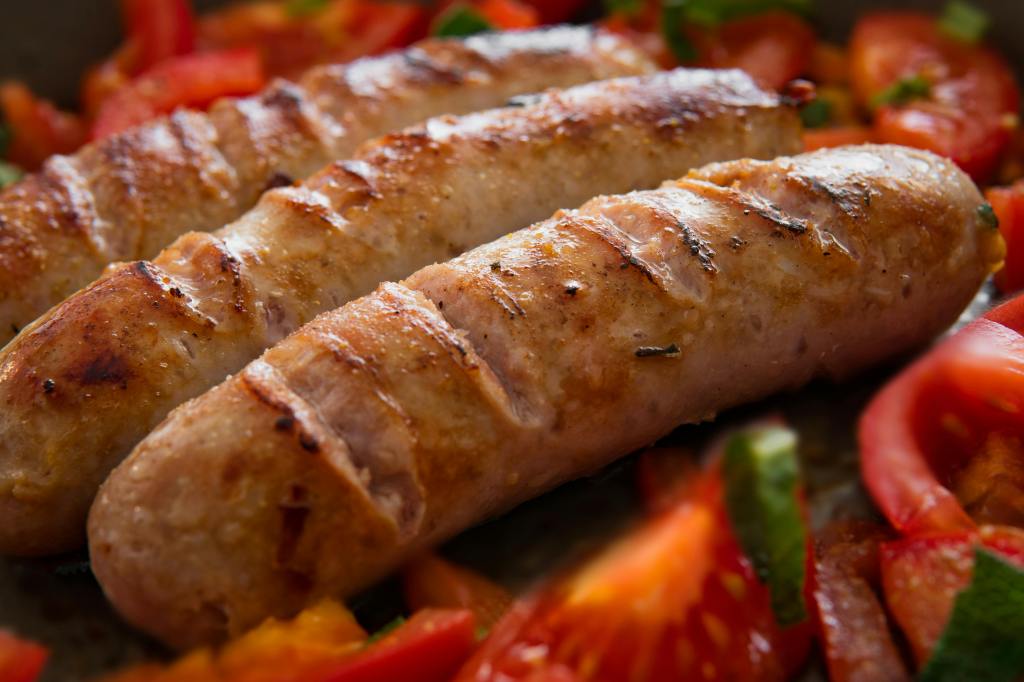three sausages on top of red and green peppers 