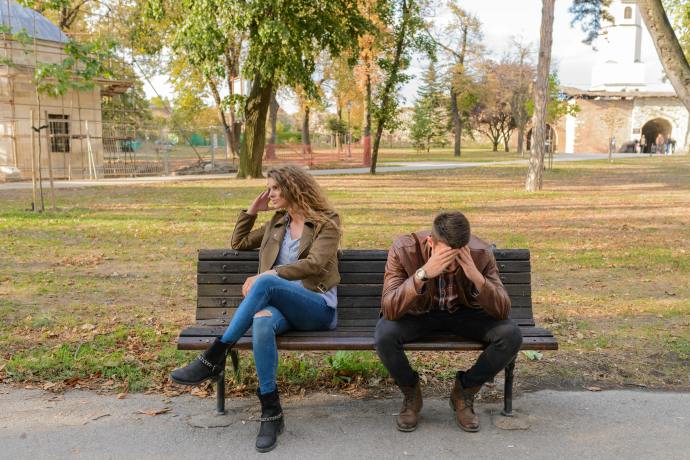 a woman and man sitting on a bench turning away from each other